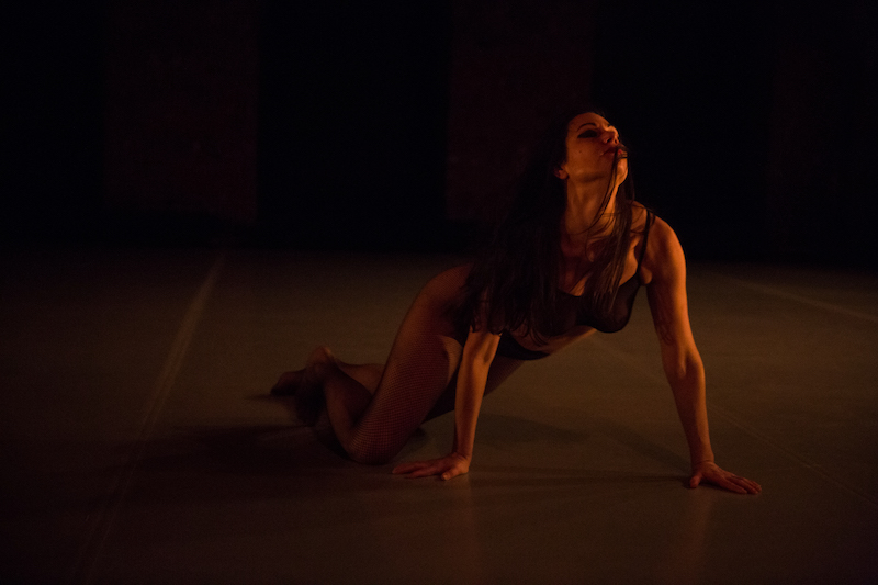 Naomi Elena Ramirez crawls on the ground. Her head upturned.